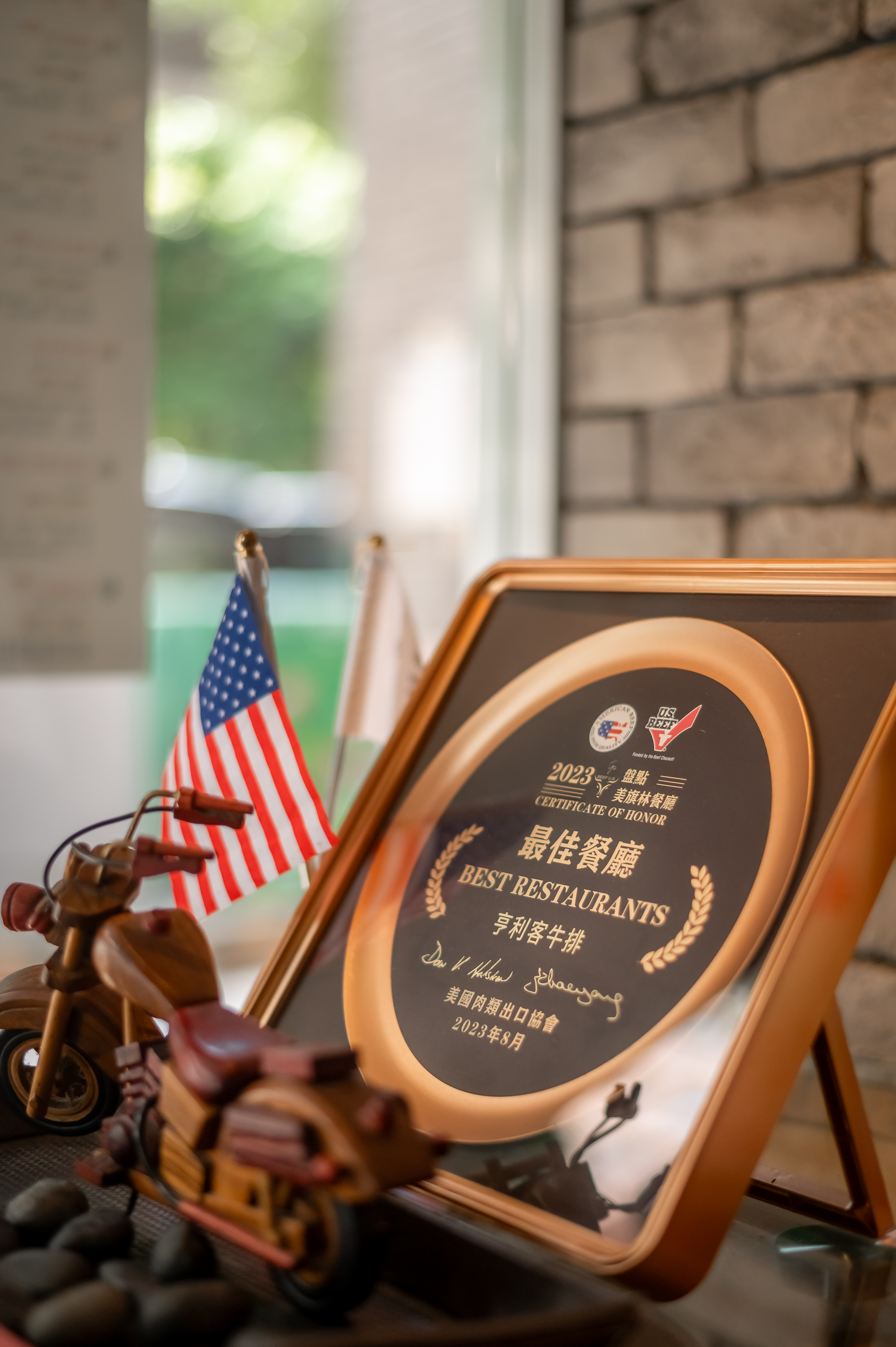 A piece of bread on a wooden plate, with butter and debris spread on it, beside a white bowl of butter, on a wooden wooden...